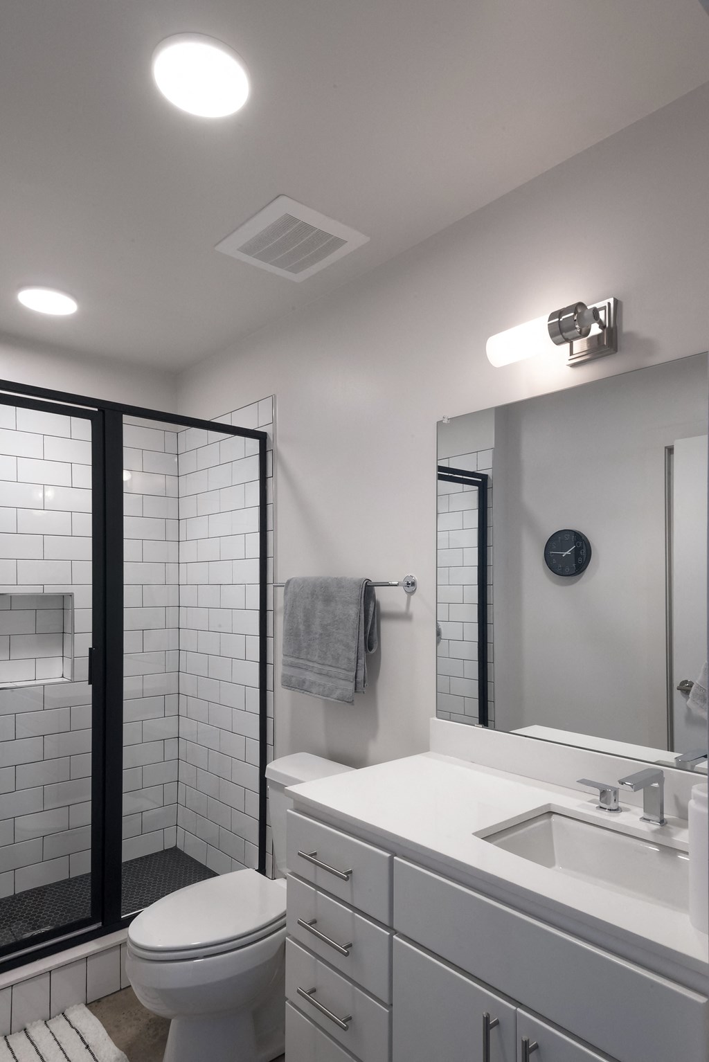 a bathroom with a white sink and toilet and a shower with a glass door